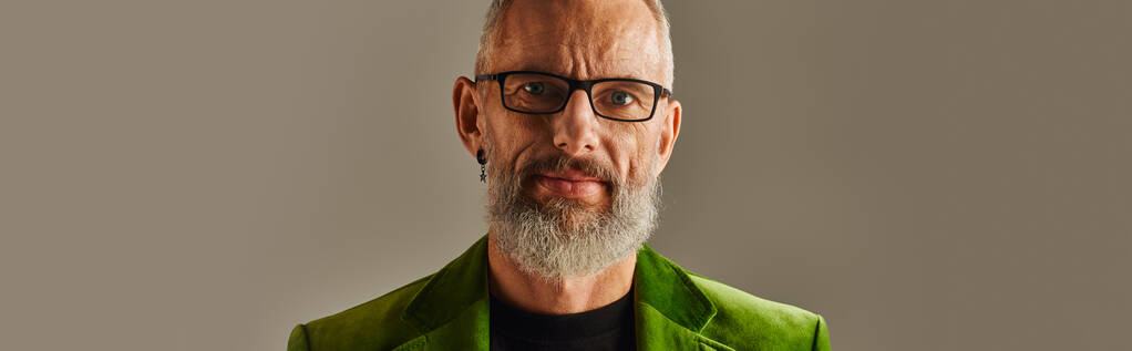 alegre guapo maduro hombre en chaqueta verde con gafas y barba mirando a la cámara, pancarta - Foto, imagen