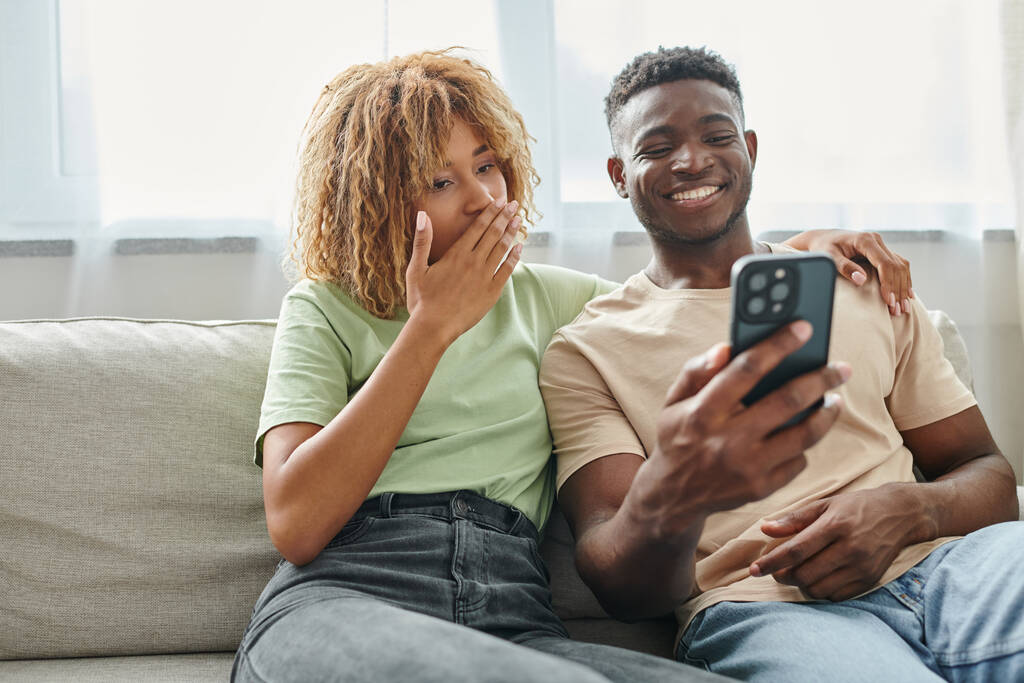 szczęśliwy afrykański amerykański para śmiech podczas wideo czat na smartfonie w domu, komunikacja - Zdjęcie, obraz