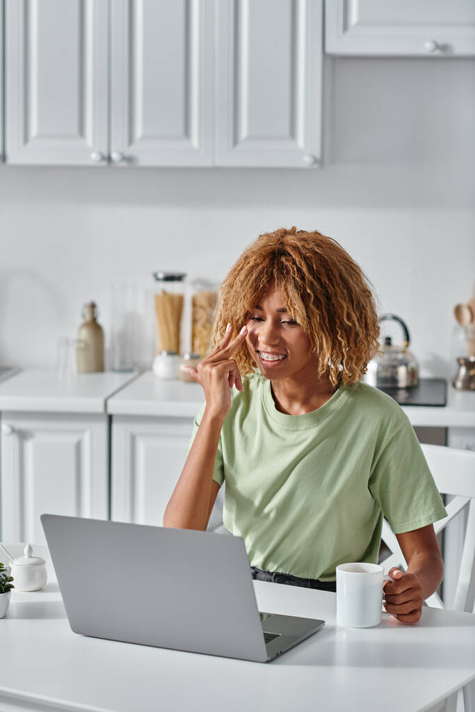 onnellinen afrikkalainen amerikkalainen nainen käyttää viittomakieltä videopuhelun aikana ja pitämällä kuppi kahvia - Valokuva, kuva