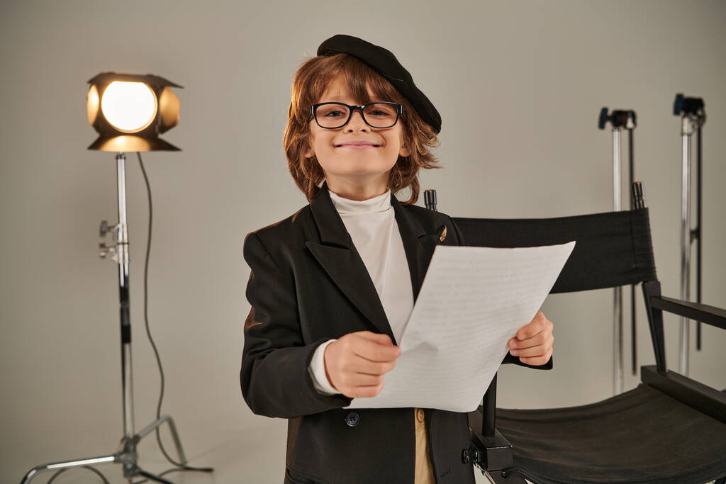 niño alegre en gafas y boina guion de lectura en papeles, niño como director de cineasta - Foto, imagen