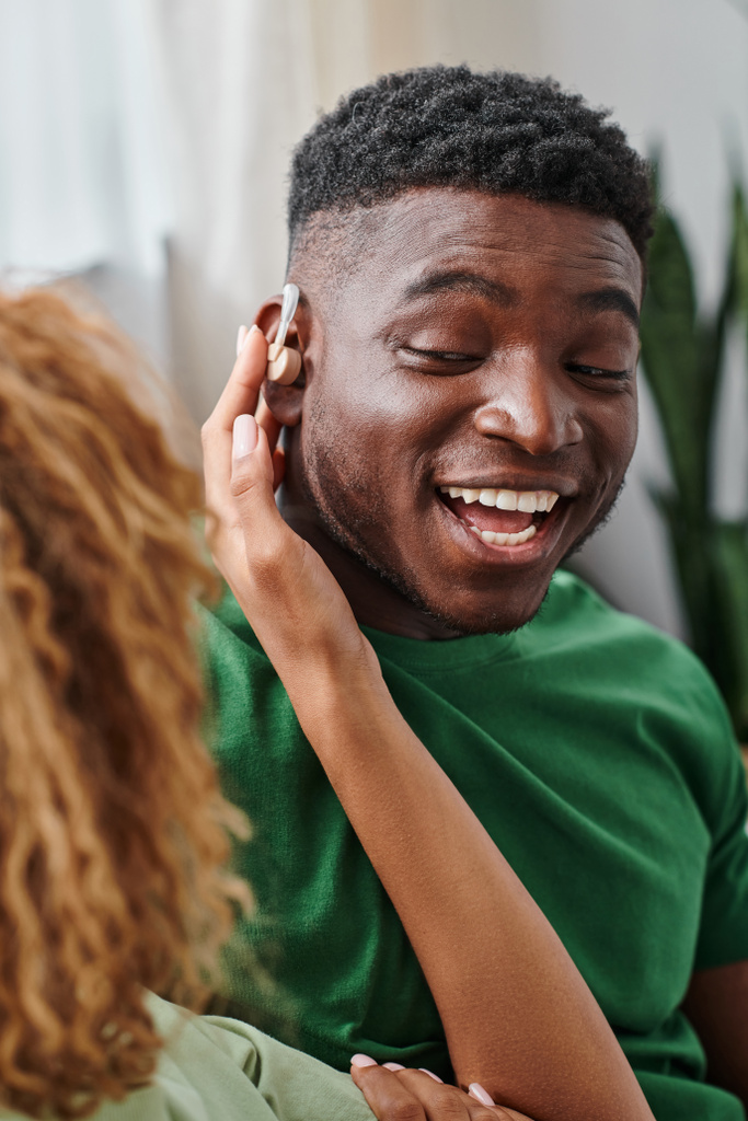 mulher afro-americana usando aparelho auditivo dispositivo médico na orelha do namorado animado, acessibilidade - Foto, Imagem