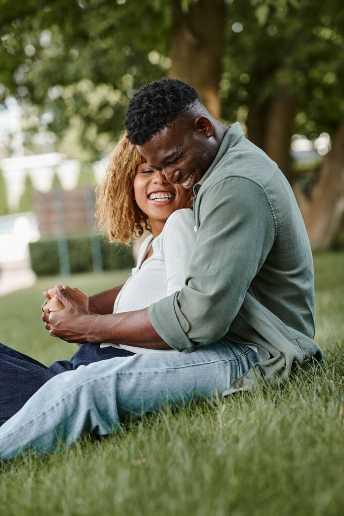 pareja afroamericana positiva pasar tiempo de calidad entre sí en el parque, tomados de la mano - Foto, imagen