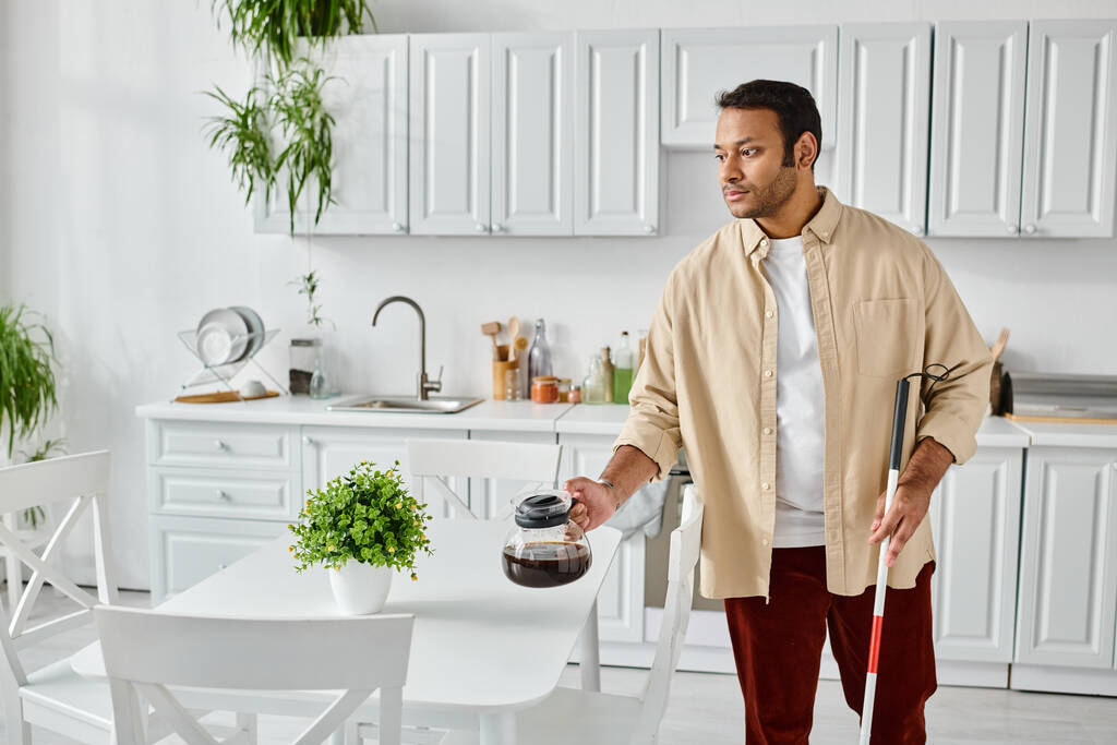 bell'uomo indiano con cecità usando bastone da passeggio e tenendo in mano la caffettiera mentre in cucina - Foto, immagini