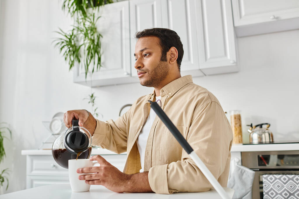 hombre indio guapo en traje casual con ceguera sentado en la mesa y vertiendo un poco de café - Foto, imagen