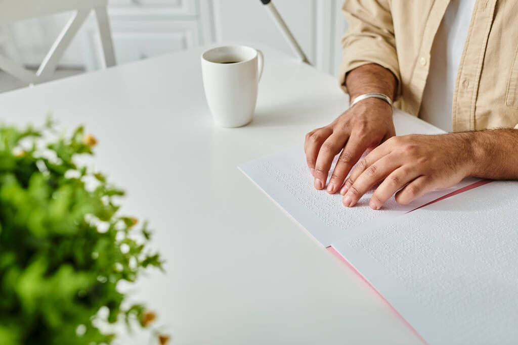 oříznutý pohled na indiánského slepce v útulném oděvu sedícího u stolu a čtoucího Braillovo písmo - Fotografie, Obrázek