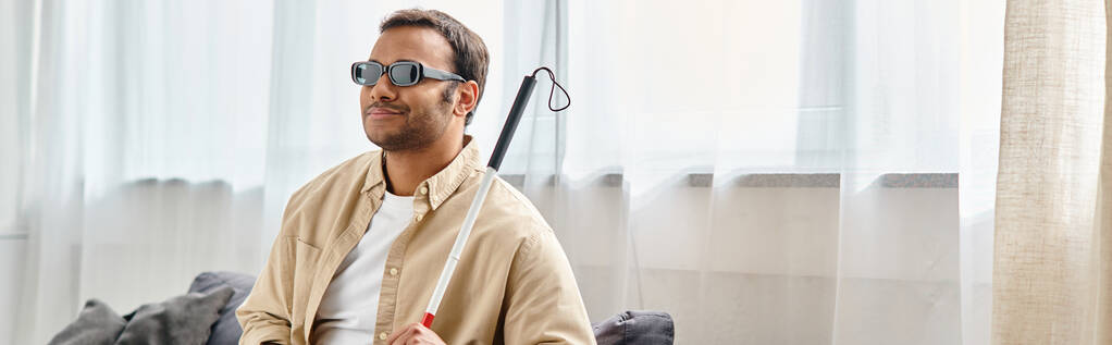 メガネとウォーキングスティックでカジュアルな衣装で視覚障害を持つ陽気なインド人男性,バナー - 写真・画像