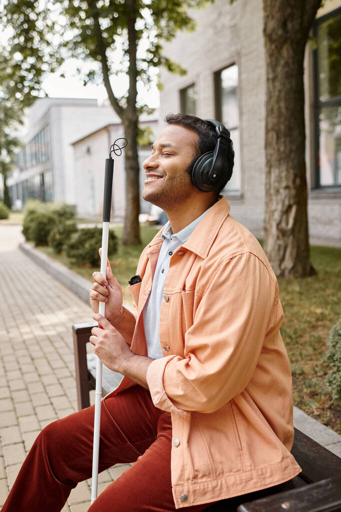 vidám fogyatékkal élő indiai férfi alkalmi felszerelés fejhallgató és sétapálca élvezi a zenét - Fotó, kép