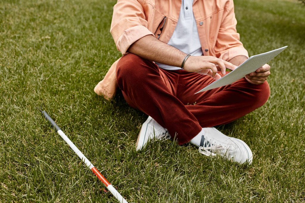 vista ritagliata di cieco indiano in giacca arancione seduto sull'erba e la lettura di codice braille - Foto, immagini