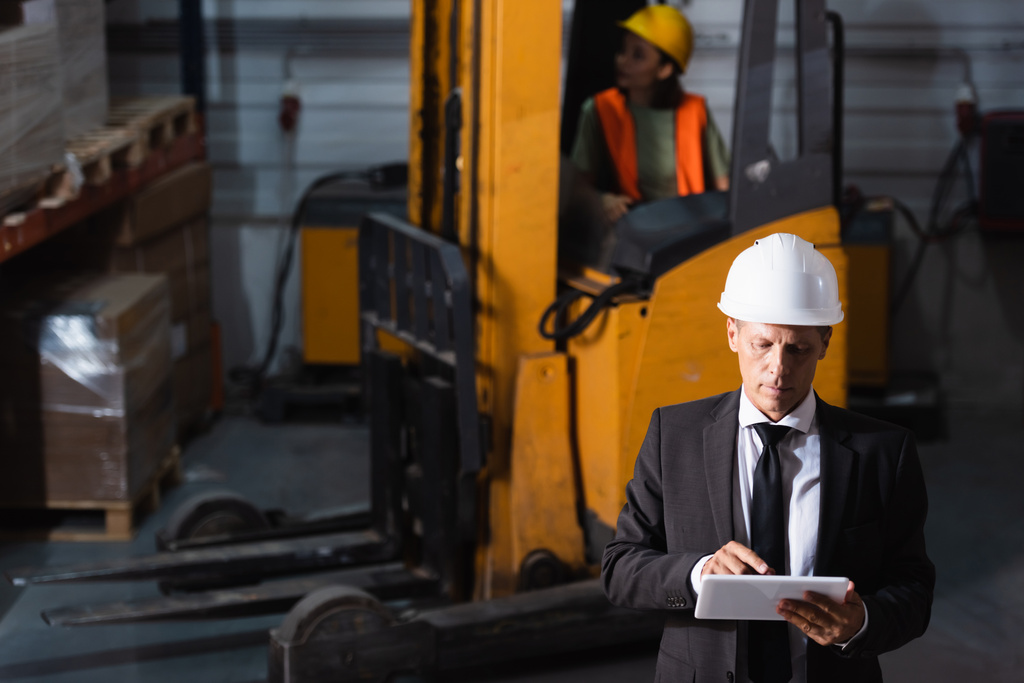 supervisor de armazém de meia idade em terno e chapéu duro usando tablet durante o planejamento de logística - Foto, Imagem