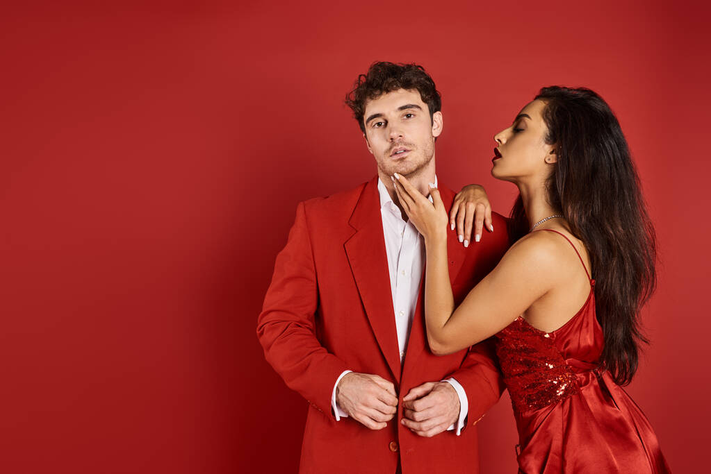 gyönyörű fiatal nő piros ajkakkal megérintette arcát jóképű férfi öltönyben Valentin napon - Fotó, kép