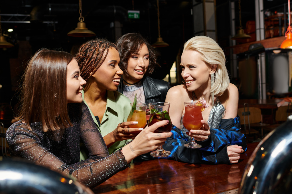 バーでヘンパーティー中にカクテルで試食するスタイリッシュな多文化女性の友人,楽しいレジャー - 写真・画像