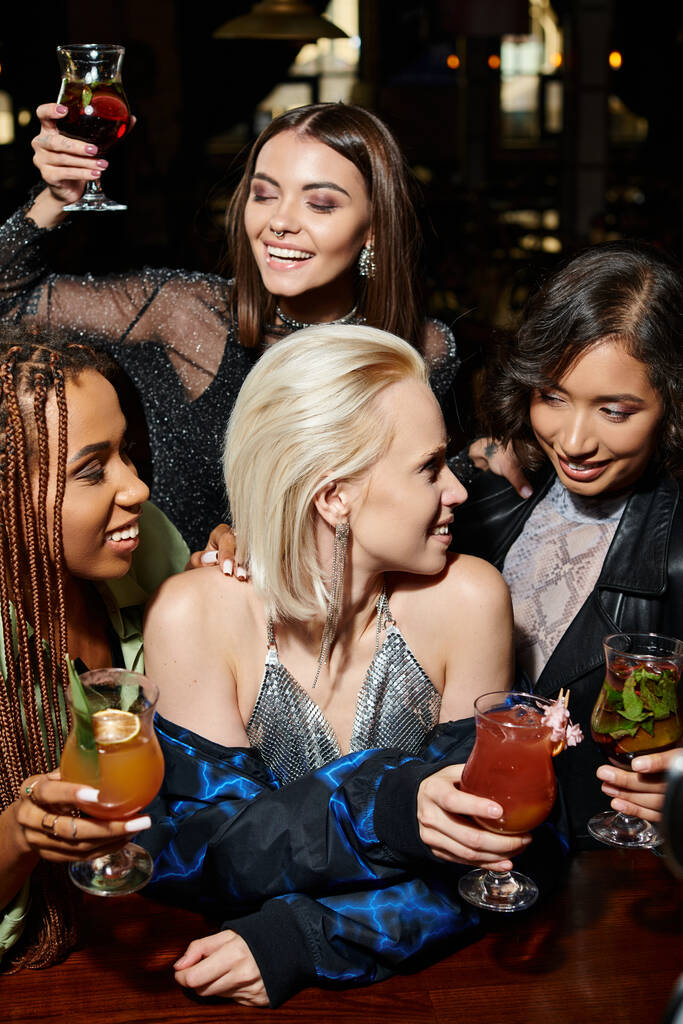 usmívající se multiiraciální elegantní ženy s lahodnými koktejly baví v baru, noční volný čas - Fotografie, Obrázek