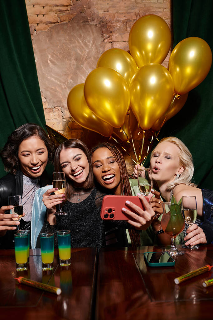 mulheres multirraciais despreocupados tomando selfie perto de coquetéis e balões dourados no bar, festa de aniversário - Foto, Imagem
