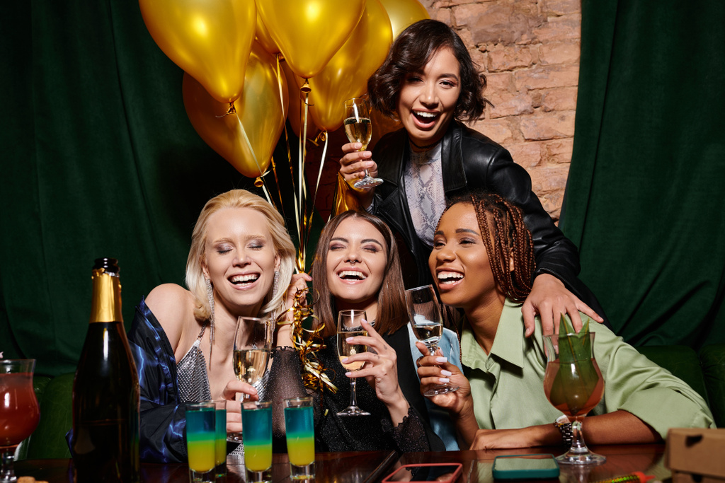 fidanzate multietniche eleganti gioiose vicino a cocktail e palloncini festivi d'oro in bar, compleanno - Foto, immagini