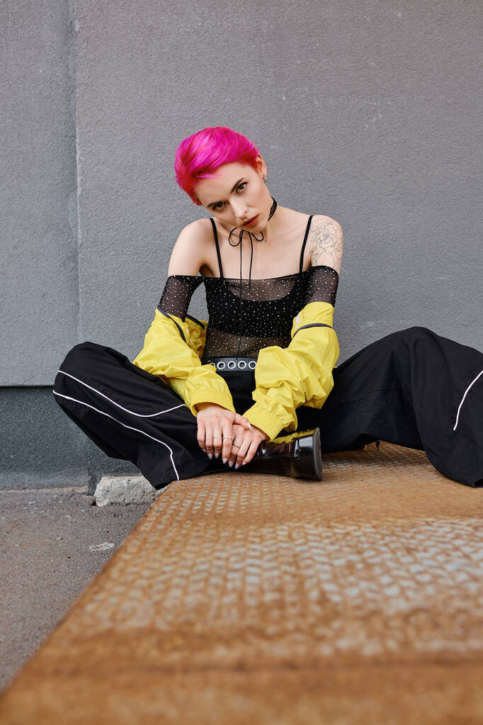 joven atractiva mujer con el pelo corto de color rosa y tatuajes sentado y mirando a la cámara, la moda - Foto, imagen