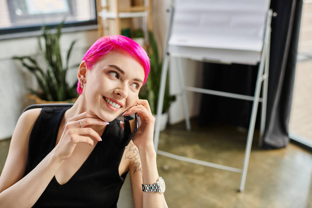 весёлая розововолосая женщина с татуировками разговаривает по телефону во время работы, бизнес-концепция - Фото, изображение