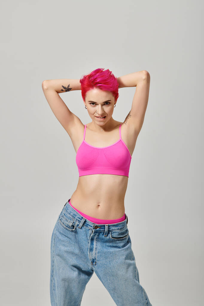 séduisante modèle féminin avec cheveux roses et tatouages posant et regardant la caméra, concept de mode - Photo, image
