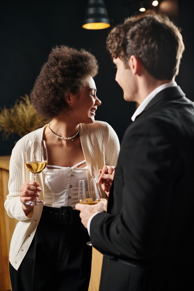 šťastný africký Američan žena drží víno sklenice a ruka muže během rande na Valentines den - Fotografie, Obrázek