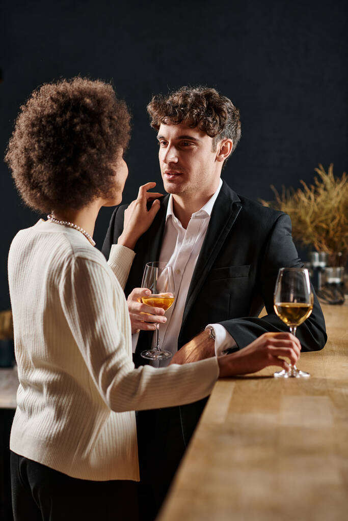 bonito homem olhando para afro americano namorada durante data no dia dos namorados, copos de vinho - Foto, Imagem