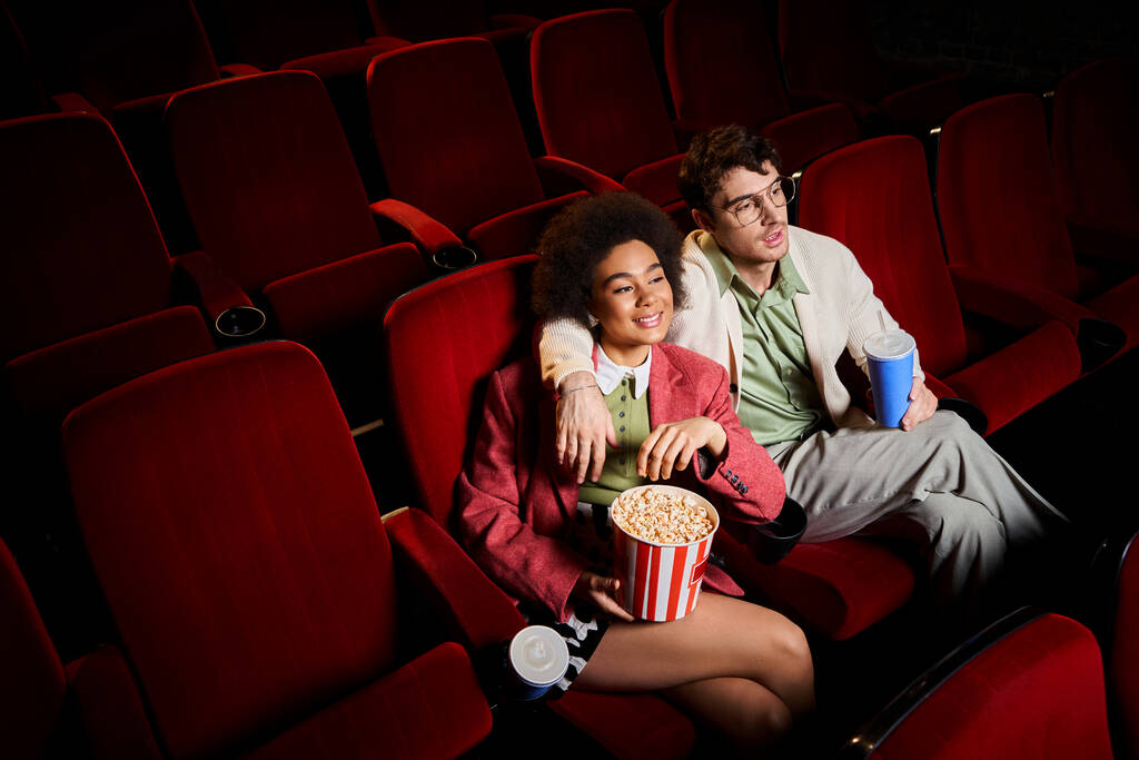 красивая, радостная, разнообразная пара в ретро стильных одеждах, смотрящая кино на свидании в кино - Фото, изображение