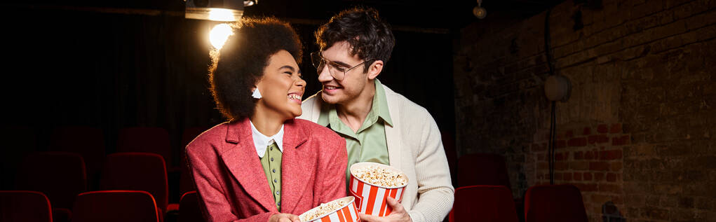 multi-etnische vrolijke paar glimlachend naar elkaar liefdevol op date in de bioscoop, Valentijnsdag, banner - Foto, afbeelding