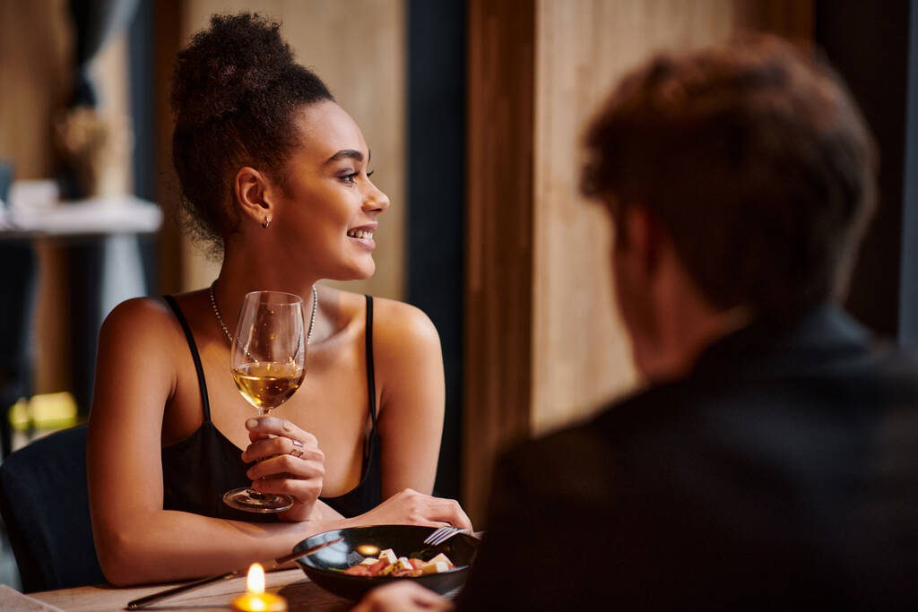 felice donna africana americana che tiene bicchiere di vino accanto al fidanzato durante la data di San Valentino - Foto, immagini