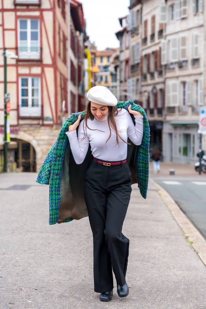 Вертикальное фото милой женщины в стильной теплой одежде, идущей по городу - Фото, изображение
