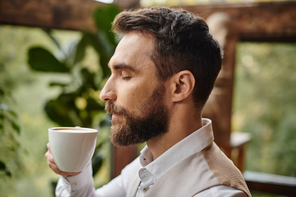 концентрированный красивый бизнес-лидер с бородой и элегантным стилем ловкости, пьющий свой кофе - Фото, изображение