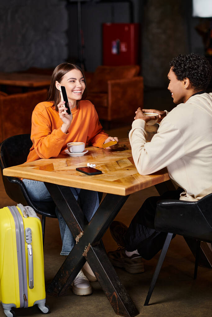 černošky muž a žena pomocí smartphone při posezení u stolu s kávou v kavárně, zavazadla a cestování - Fotografie, Obrázek