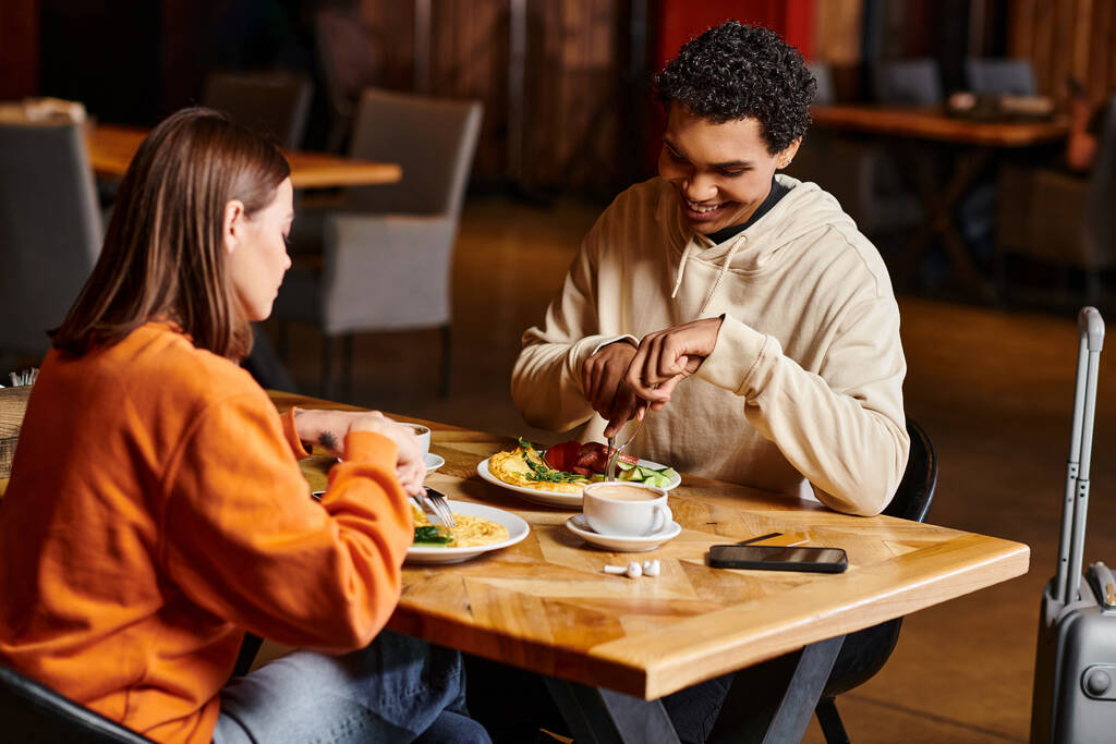 diversos casal compartilha refeição em um restaurante, seus rostos iluminados com alegria enquanto desfrutam de comida saborosa - Foto, Imagem