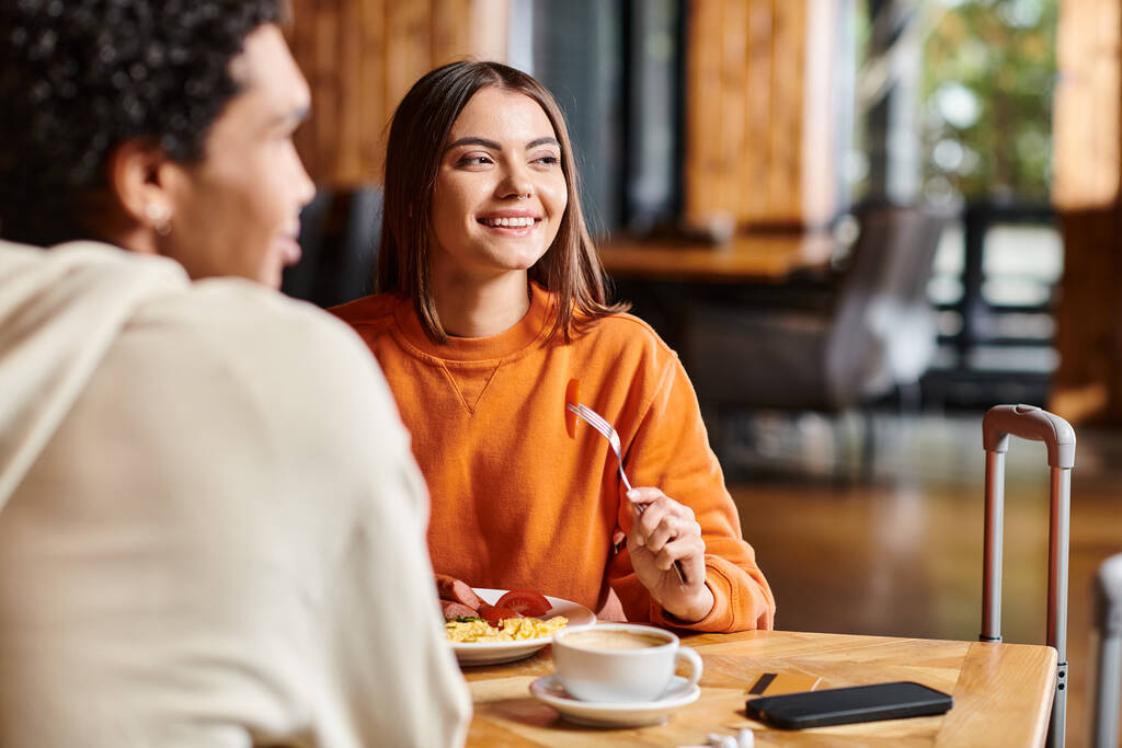 Hymyilevä nuori nainen, jolla on ihana aamiainen poikaystävän kanssa viihtyisässä kahvilassa - Valokuva, kuva