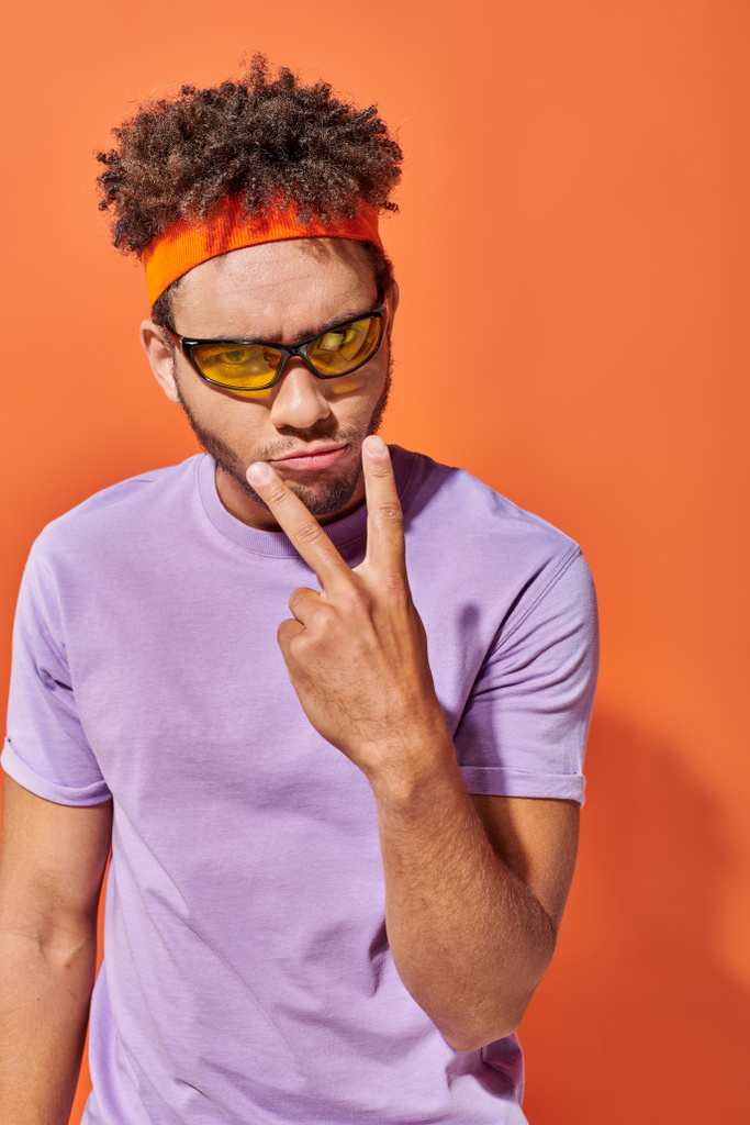 expression sérieuse, jeune homme afro-américain faisant un geste de contact visuel sur fond orange - Photo, image