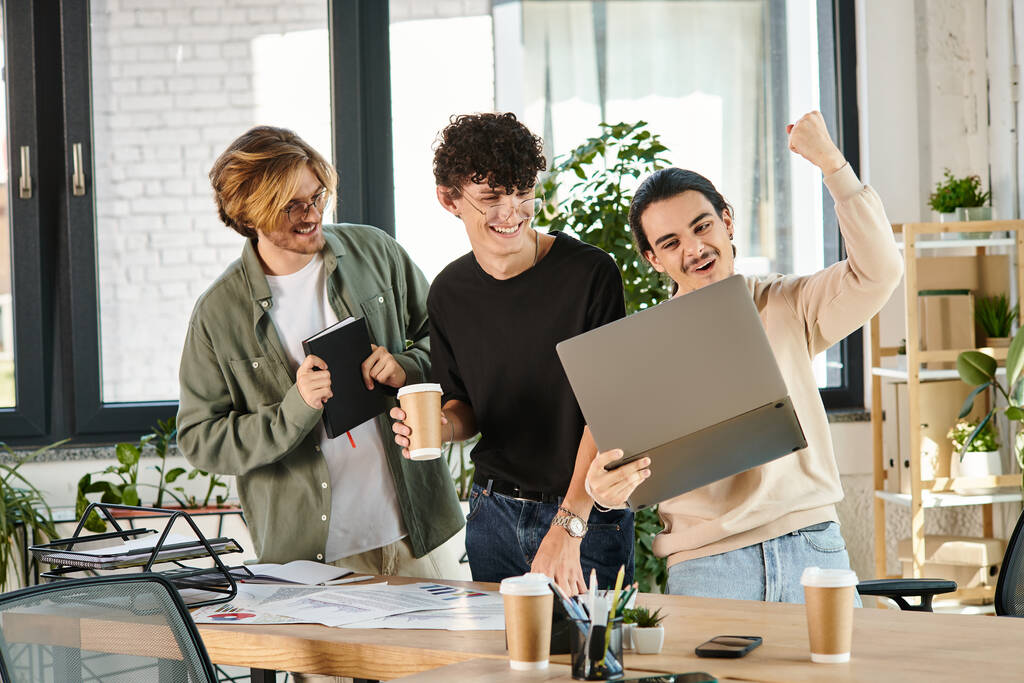 Drei junge Männer in einer lebhaften Diskussion über einen Laptop in einem Coworking Space, Erfolg - Foto, Bild