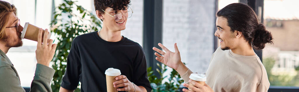 φιλική συνομιλία μεταξύ τριών νέων συναδέλφων κρατώντας καφέ για να πάει στο σύγχρονο γραφείο, πανό - Φωτογραφία, εικόνα