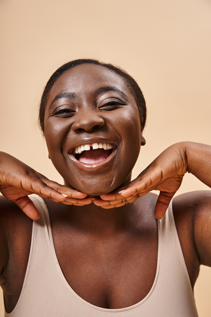 šťastný plus velikost africký americký žena s rukama v blízkosti její tváře proti odpovídající pozadí - Fotografie, Obrázek