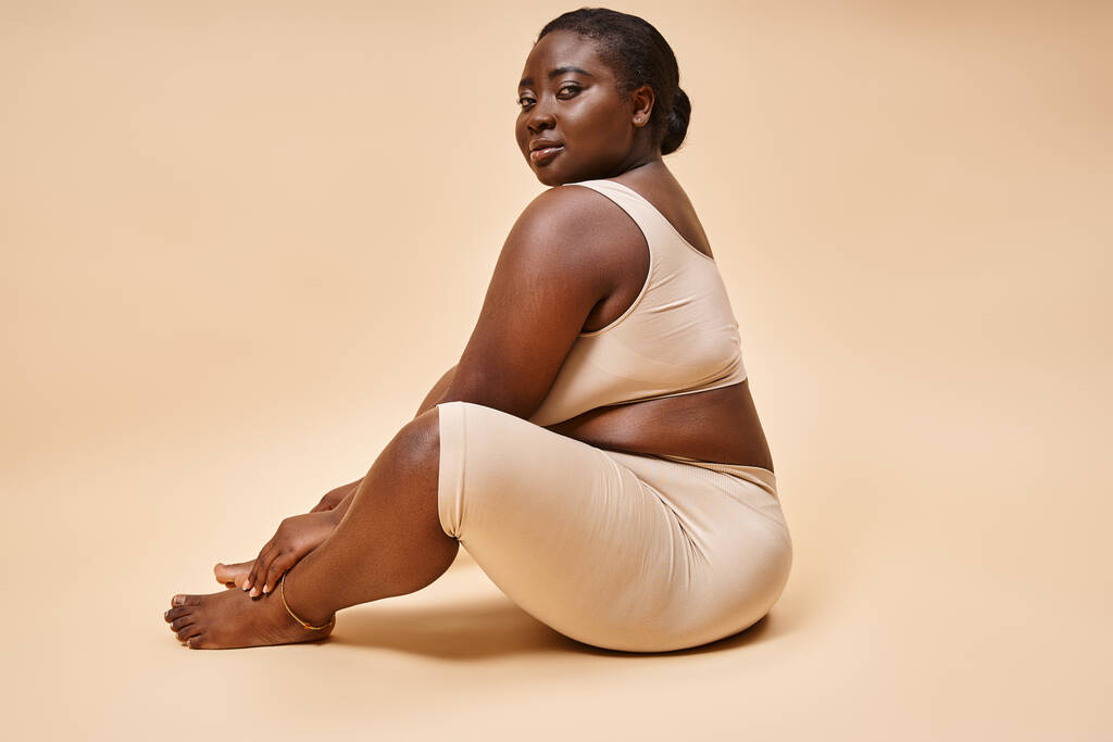Vücut pozitifliği, artı bej arka planda iç çamaşırlı Afrikalı Amerikalı kadın. - Fotoğraf, Görsel