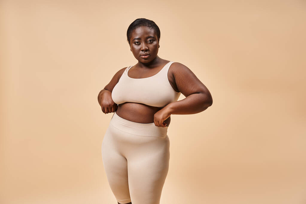 mujer de talla grande en ropa interior posando sobre fondo beige, potenciación corporal positiva y femenina - Foto, Imagen