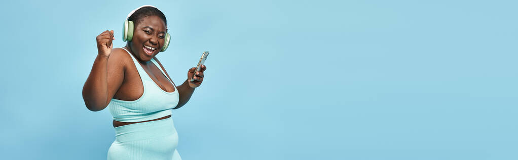 plus la taille femme afro-américaine écouter de la musique dans les écouteurs connectés au smartphone, bannière - Photo, image