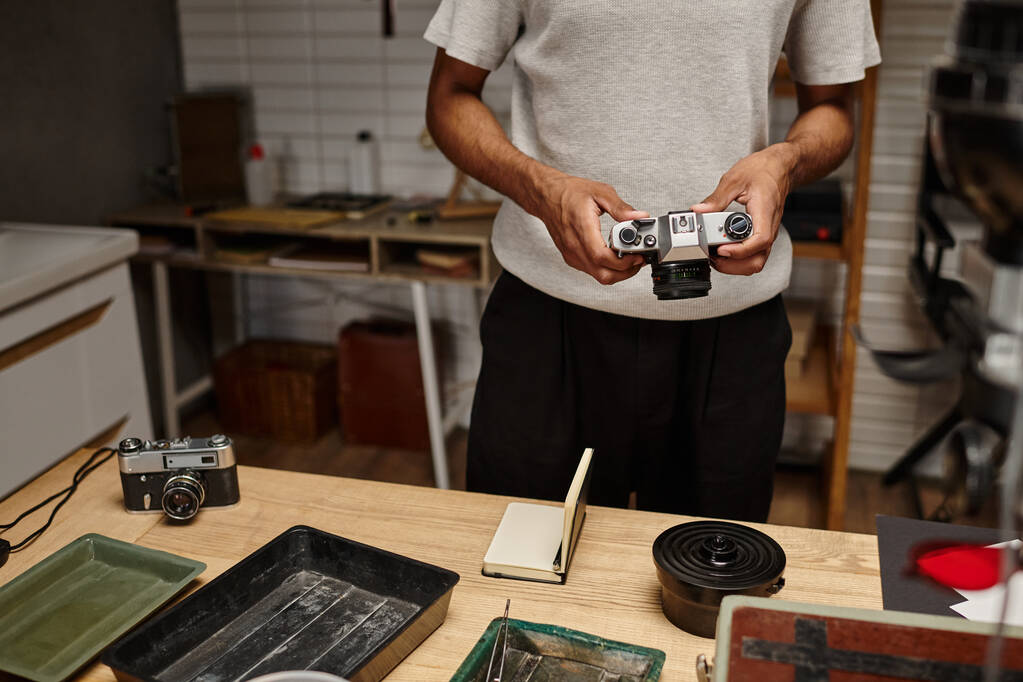 vista recortada del fotógrafo afroamericano manejando expertamente una cámara vintage en el laboratorio de fotografía - Foto, Imagen