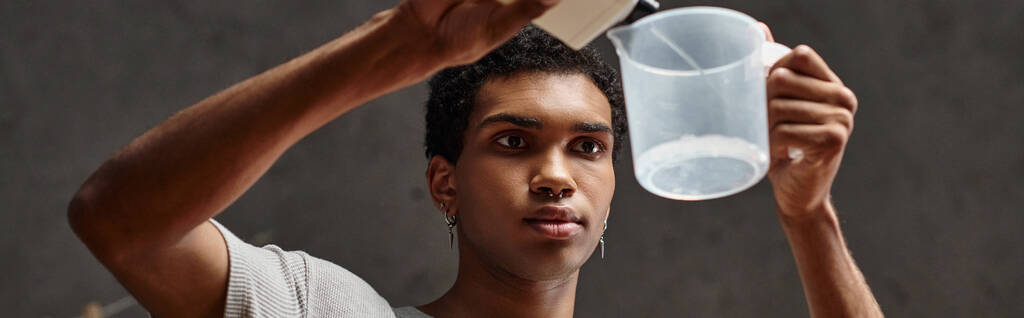 όμορφος αφρικανός Αμερικανός άνθρωπος ρίχνει χημικό διάλυμα σε κύπελλο μέτρησης, banner της ανάπτυξης ταινιών - Φωτογραφία, εικόνα