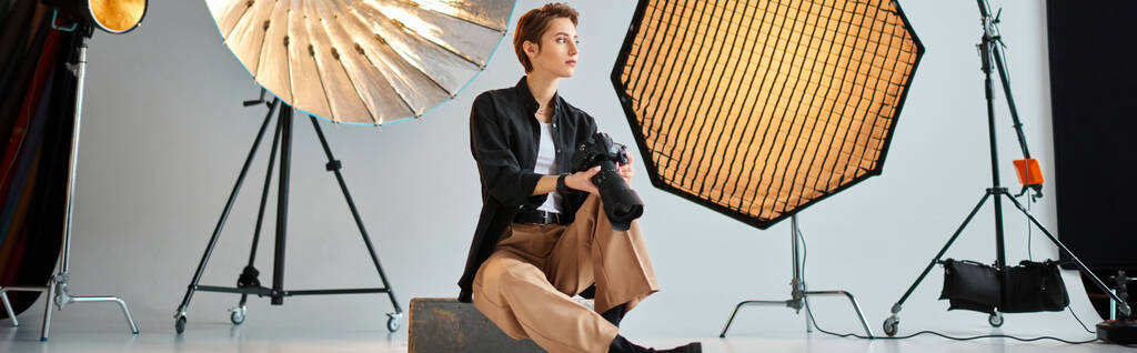 красивая молодая женщина-фотограф в повседневной одежде позирует в своей студии и смотрит в сторону, баннер - Фото, изображение