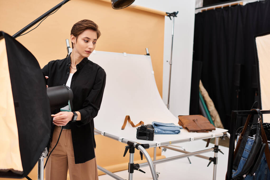 потрясающая молодая женщина-фотограф в повседневной одежде работает со своим оборудованием в студии - Фото, изображение
