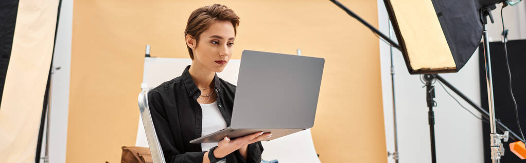 pretty short haired photographer sitting and retouching photos in studio using her laptop, banner - Photo, Image
