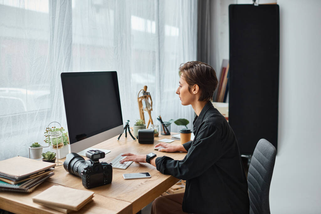 charmante professionele vrouwelijke fotograaf in casual dragen retoucheren foto 's op de computer in haar studio - Foto, afbeelding