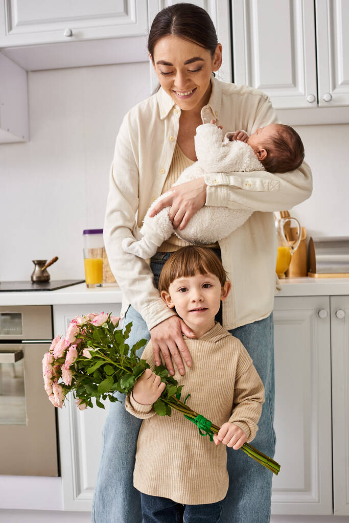 opiekuńcza wesoła rodzina w gospodarstwie domowym pozowanie z bukietem kwiatów podczas pobytu w kuchni, nowoczesne rodzicielstwo - Zdjęcie, obraz