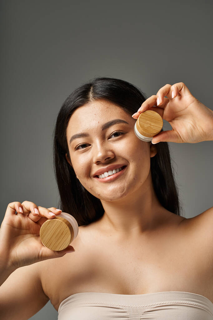 mujer asiática joven con pelo morena y piel propensa al acné mirando el espejo en el baño, pancarta - Foto, imagen