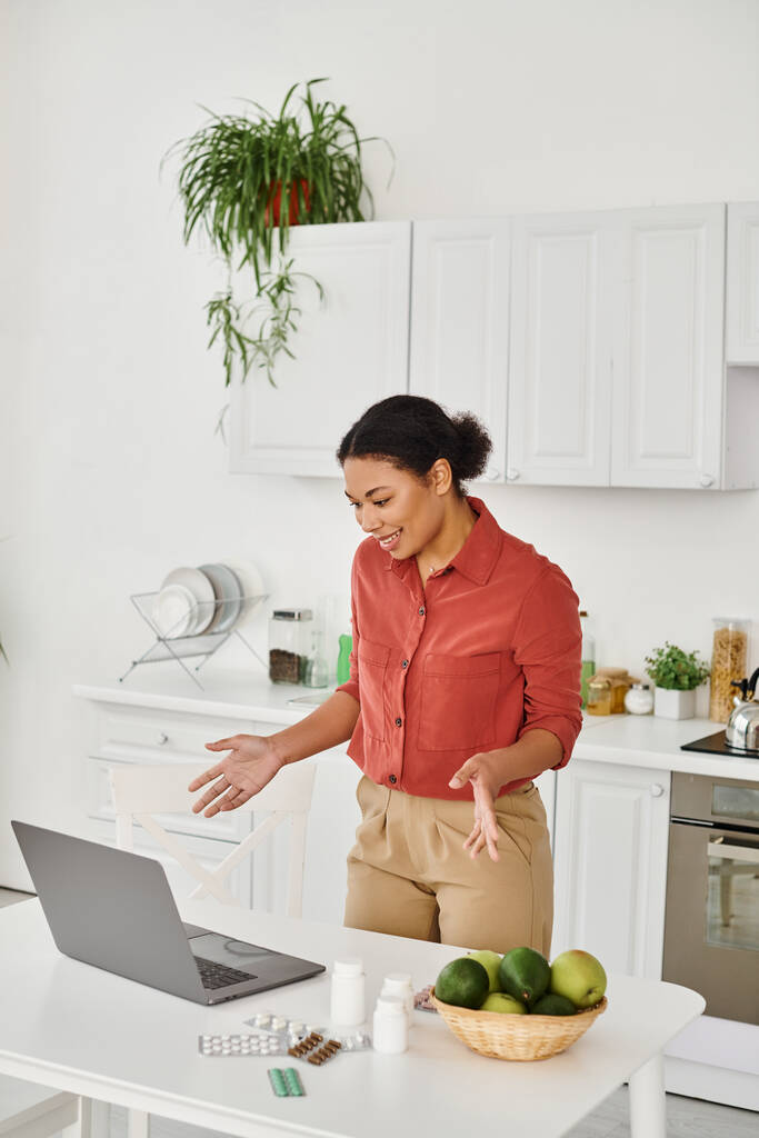 african american nutritionist gesturing while standing near laptop and offering diet advice online - Photo, Image