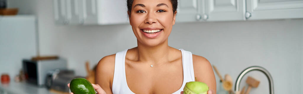 pancarta de mujer afroamericana con cinta métrica y frutas promoviendo una dieta saludable en la cocina - Foto, Imagen