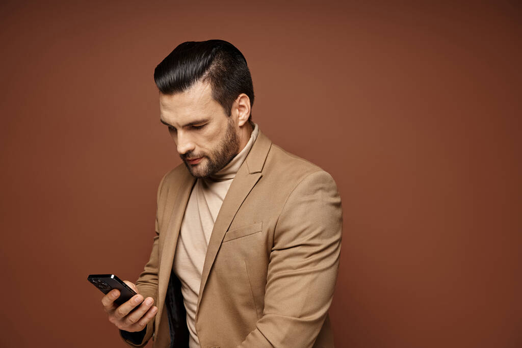 όμορφος επιχειρηματίας με κομψή ενδυμασία ελέγχει το smartphone του σε μπεζ φόντο, δικτύωση - Φωτογραφία, εικόνα