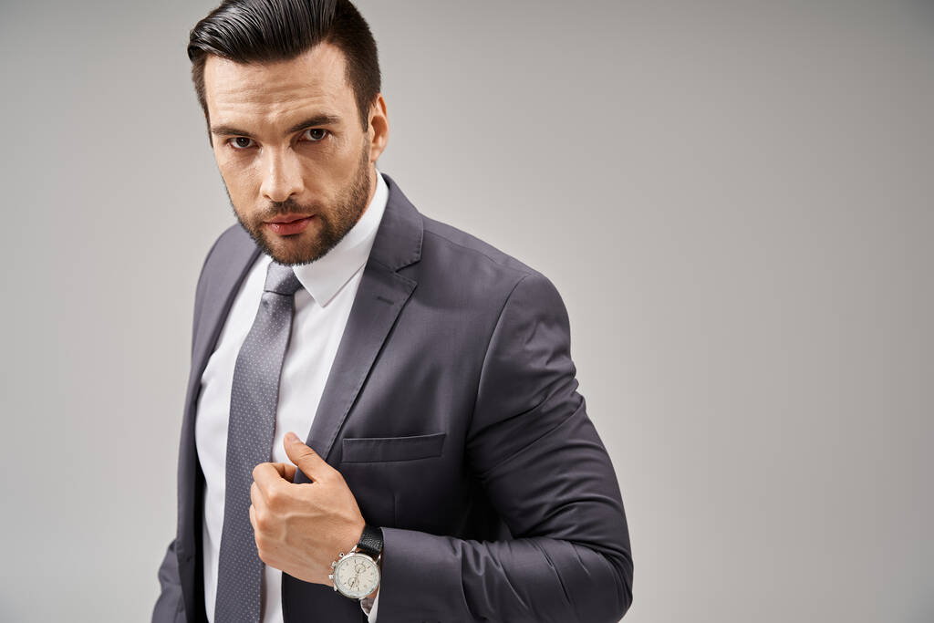 Charismatic businessman in suit with a confident stance looking at camera on grey background - Photo, Image